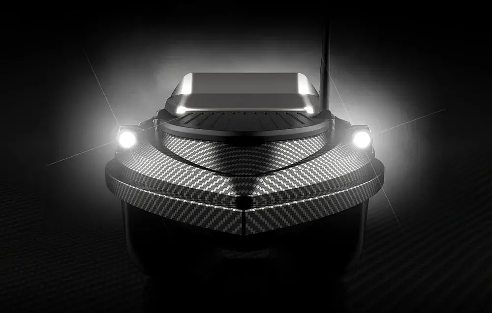 RC karbonová vnadící loď zepředu se dvěma silnými bílými LED reflektory na černém pozadí